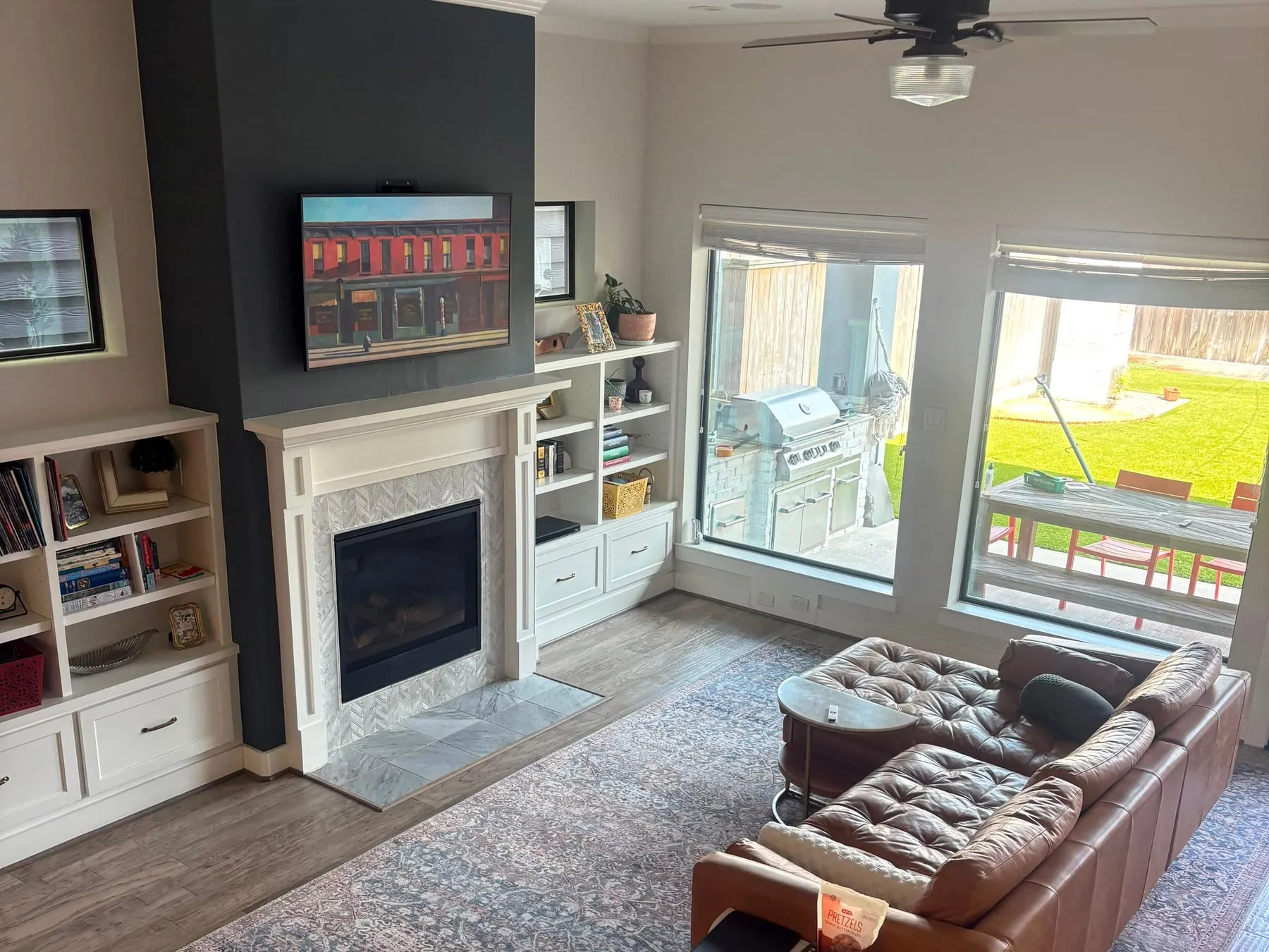 Den with a leather sofa, a tiled fireplace and white built-in shelving dusted, rug and floor cleaned