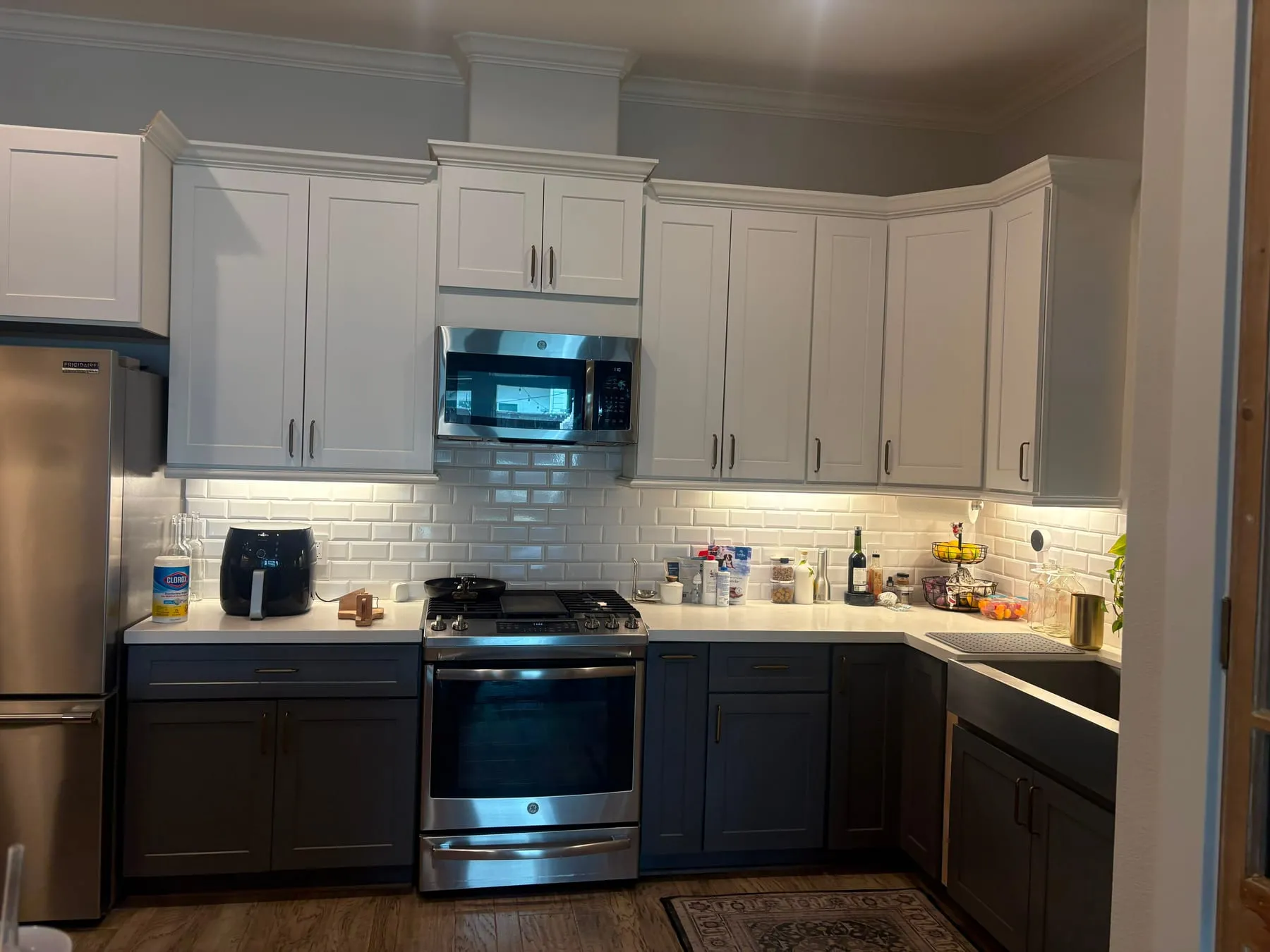 Kitchen with white and charcoal cabinets, a subway-tile backsplash and a stainless range, cleaned from the cabinet tops to the floor