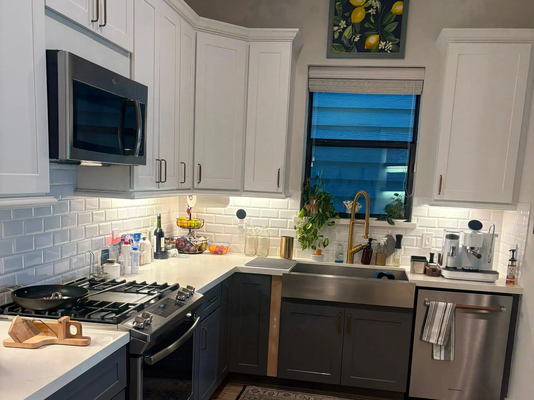 Kitchen counters and subway-tile backsplash wiped down, with a stainless farmhouse sink and a polished brass tap